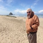 Photo of Doug, standing on a beach near Haystack Rock, Cannon Beach, Oregon.